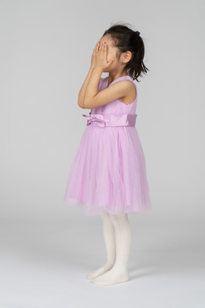 Девушка в розовом платье прячет лицо