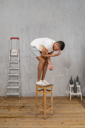 Man bending down and touching his forehead