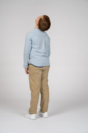 Vista trasera del niño con ropa informal mirando hacia arriba