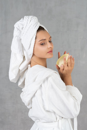 一个穿着浴袍的女人拿着一桶奶油的侧视图