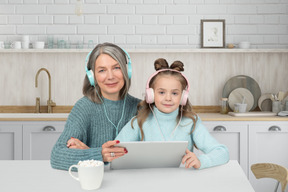 A woman and a girl sitting at a table with headphones on