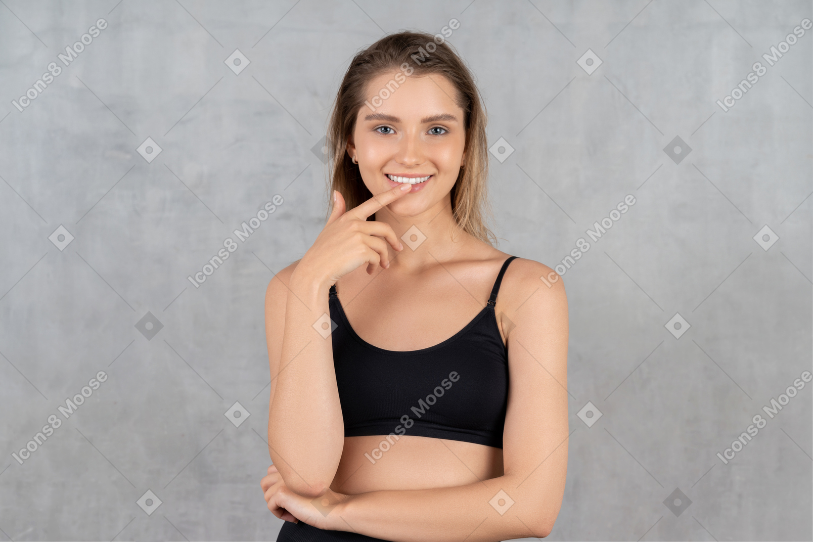 Beautiful woman holding finger on lip while smiling