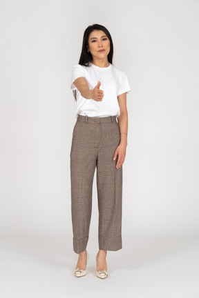 Front view of a greeting young lady in breeches and t-shirt outstretching her hand