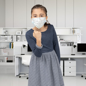 Little girl in face mask threatening with a clenched fist