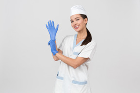Attraktive krankenschwester in einem medizinischen gewand, das einen latexhandschuh überzieht