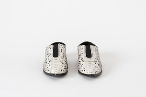 Una foto frontal de un par de zapatos planos de piel de serpiente blancos y negros