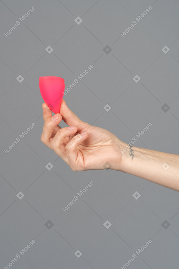 Close up of a hand holding menstrual cup over gray background
