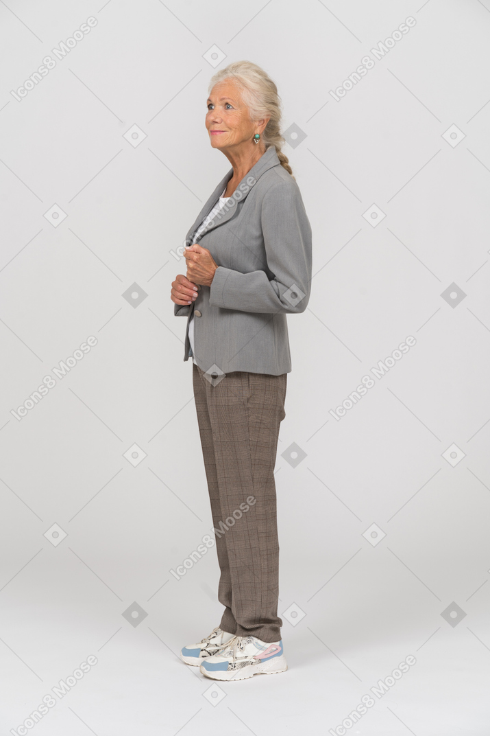 Old woman n grey jacket standing in profile
