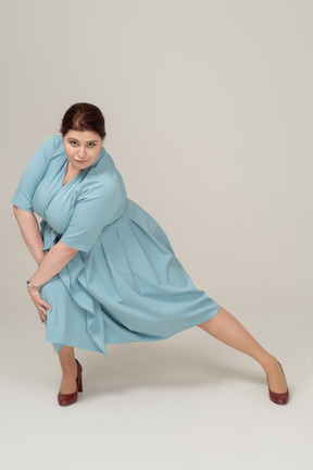 Вид спереди женщины в синем платье упражнения