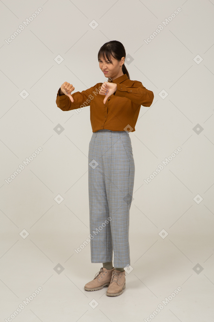 Three-quarter view of a young asian female in breeches and blouse showing thumbs down