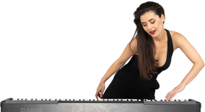 Вид спереди молодой дамы в черном платье, положив руку на клавиатуру и откинувшись в сторону