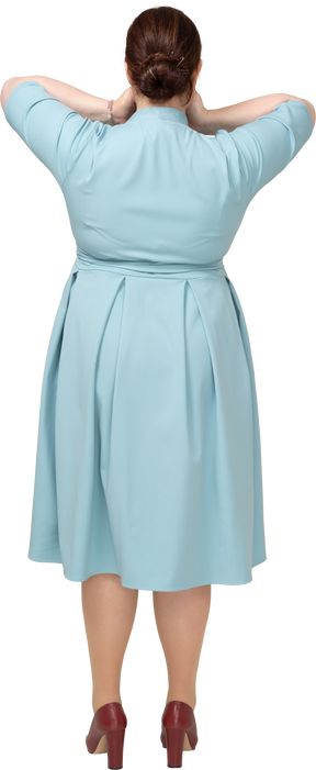 手で口を覆う青いドレスを着た女性の背面図