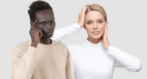 Man with finger on temple standing next to woman with hands on her face