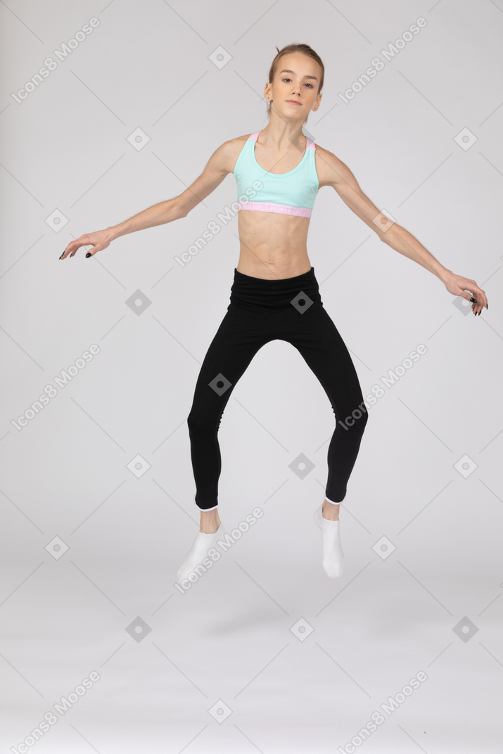 Seitenansicht eines jugendlich mädchens in der sportbekleidung, die hockt und hände auf hüften setzt