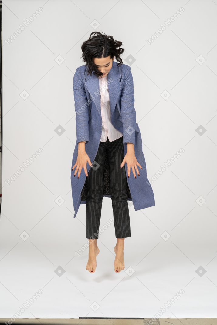 Mujer joven en abrigo levitando