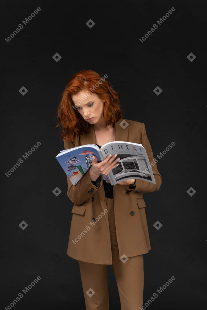 Vista frontal de uma jovem empresária lendo uma revista