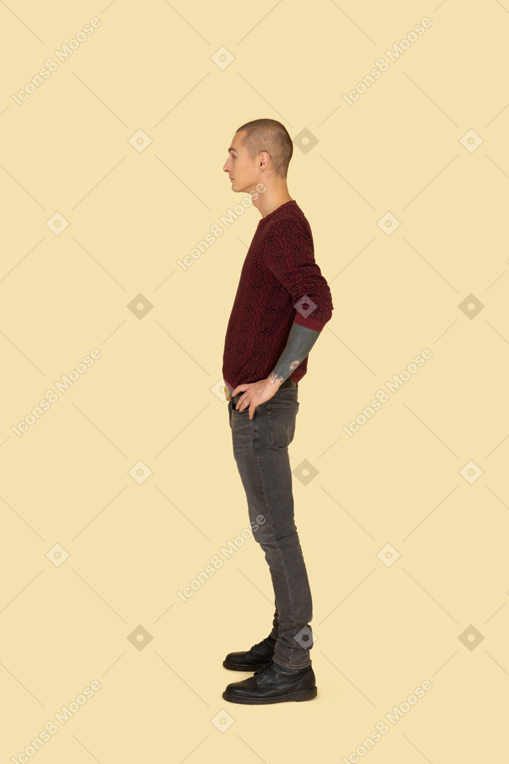 Seitenansicht eines jungen mannes im pullover, der hände auf hüften setzt