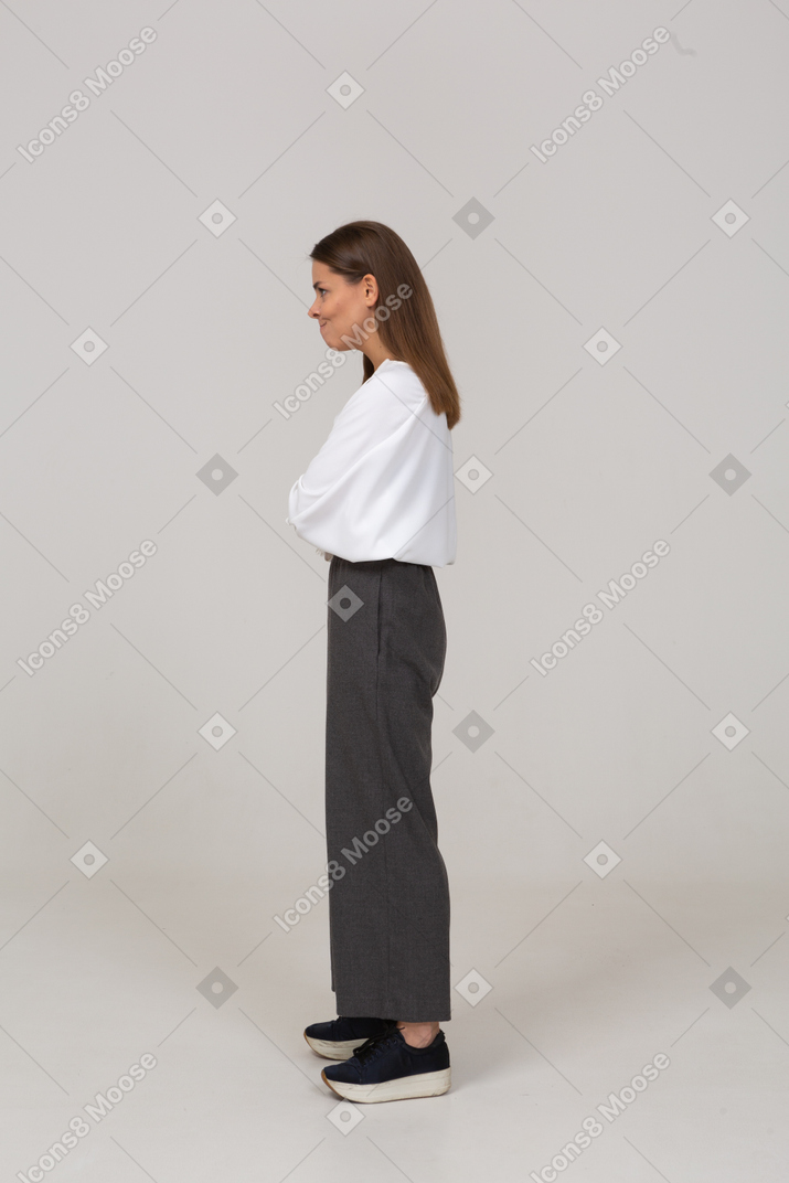 Side view of an offended young lady in office clothing pressing lips and crossing arms