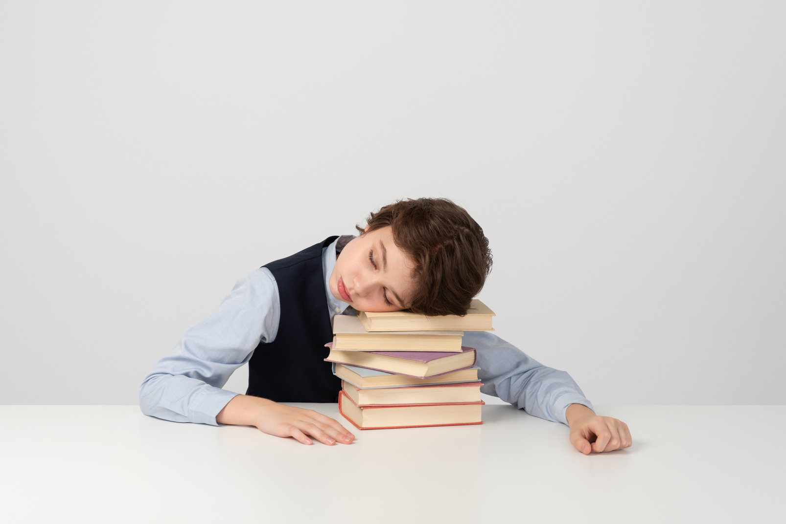 Tired schoolboy sleeping on a bunch of books