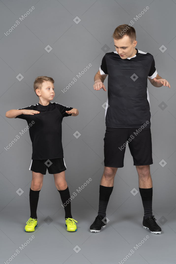 Молодой человек тренирует маленького мальчика в полный рост, делая разминку