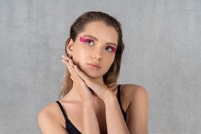 Retrato de una mujer joven con maquillaje de ojos rosa brillante soñando despierta