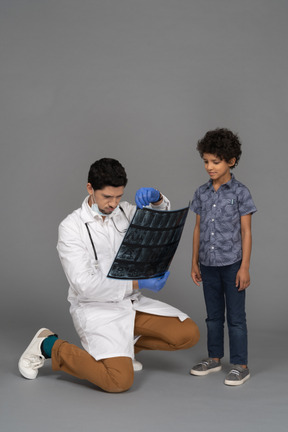 Médico y niño examinando la imagen de rayos x.