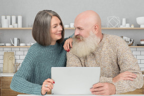 An older couple looking at a laptop in the kitchen