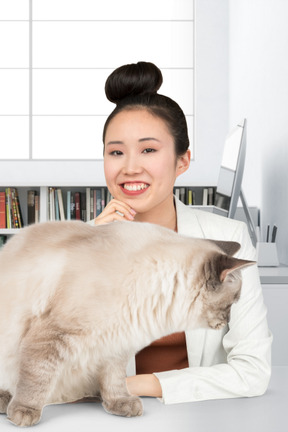 Asiatisches mädchen, das mit ihrer katze an einem tisch sitzt