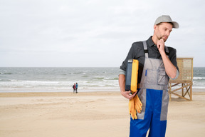 Pensive electrician standing on the beach