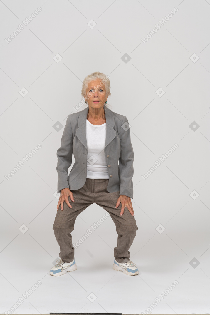 Front view of an old lady in suit squatting