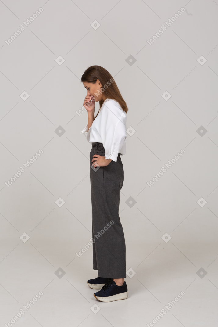 Side view of a thoughtful young lady in office clothing touching nose