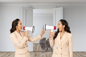 A couple of women standing next to each other holding megaphones