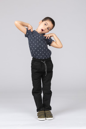 Vue de face d'un garçon mignon dans des vêtements décontractés posant avec les mains sur les épaules