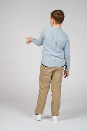 Back view of a boy standing with extended arm
