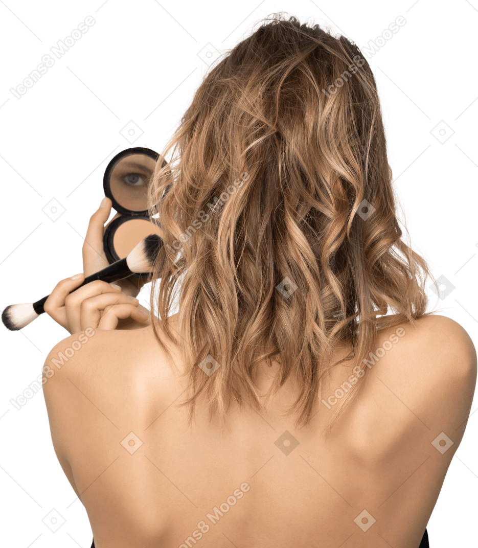 Vista posteriore di una giovane donna che applica cipria mentre tiene in mano uno specchio