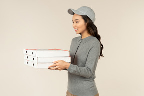 Young asian pizza delivery girl holding pizza boxes