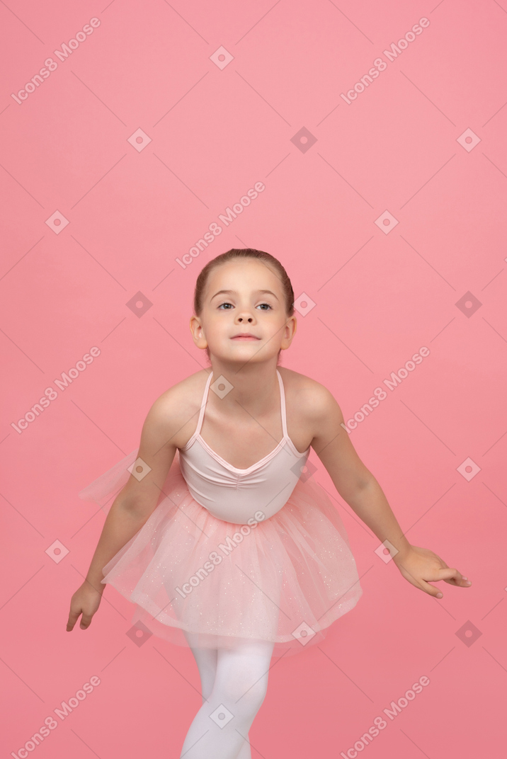 站立用她的手的芭蕾舞短裙的小女孩在旁边