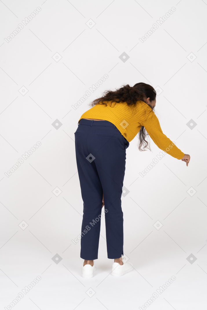 Rear view of a girl in casual clothes bending down with extended hand