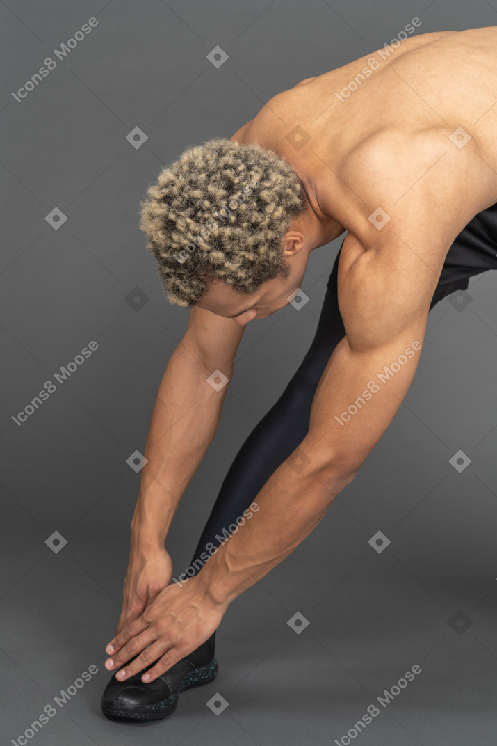 Shirtless man reaching down to his toes