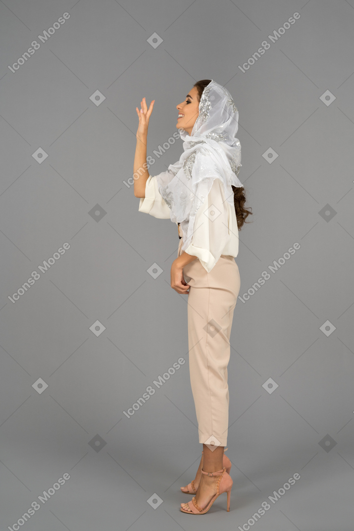 Covered young woman waving with a hand in profile