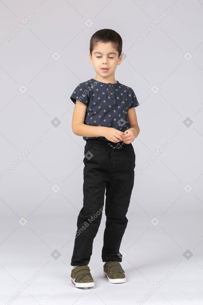 Front view of a cute boy in casual clothes standing with closed eyes