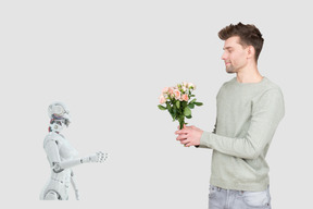 A man holding a bouquet of flowers next to a robot