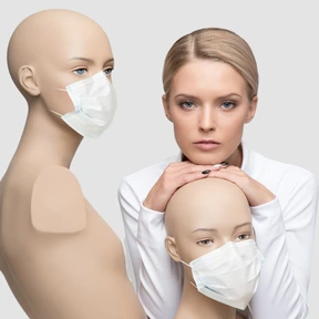 A woman standing next to a couple of mannequins in face masks 