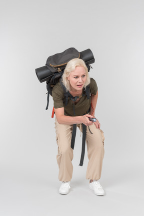 Carrying backpack mature female tourist using dictaphone