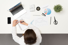 Um trabalhador de escritório feminino fazendo anotações na mesa