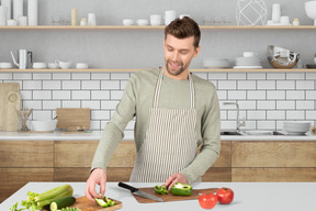 A man in a kitchen cutting vegetables on a cutting board