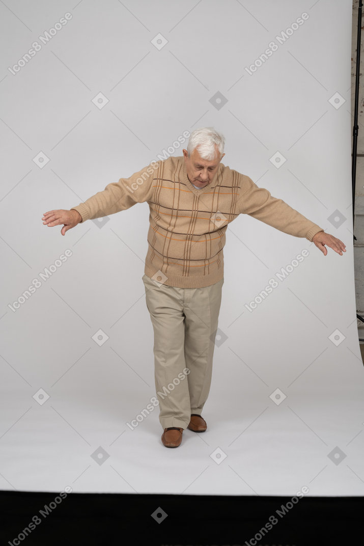 Vorderansicht eines alten mannes in freizeitkleidung, der mit ausgestreckten armen vorwärts geht