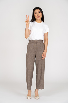 Front view of a young woman in breeches showing peace sign