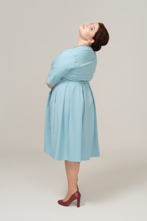 Vista laterale di una donna in abito blu che guarda in alto