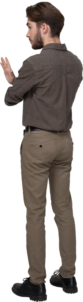 Three-quarter back view of a young man in office clothing crossing arms